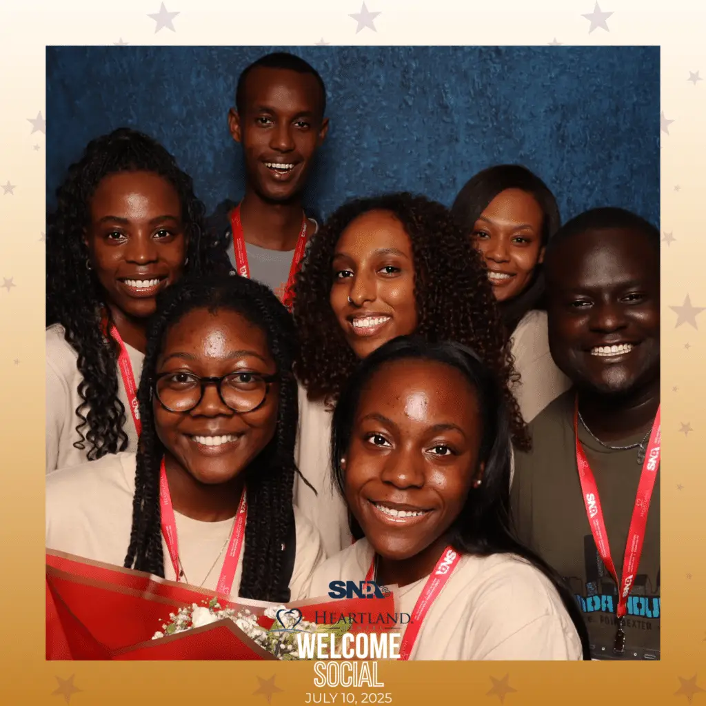 Seven attendees smiling together at the SNDA Heartland Welcome Social branded photo booth experience, July 10, 2025 — custom overlay with event logo and gold star frame by Lumen Activations