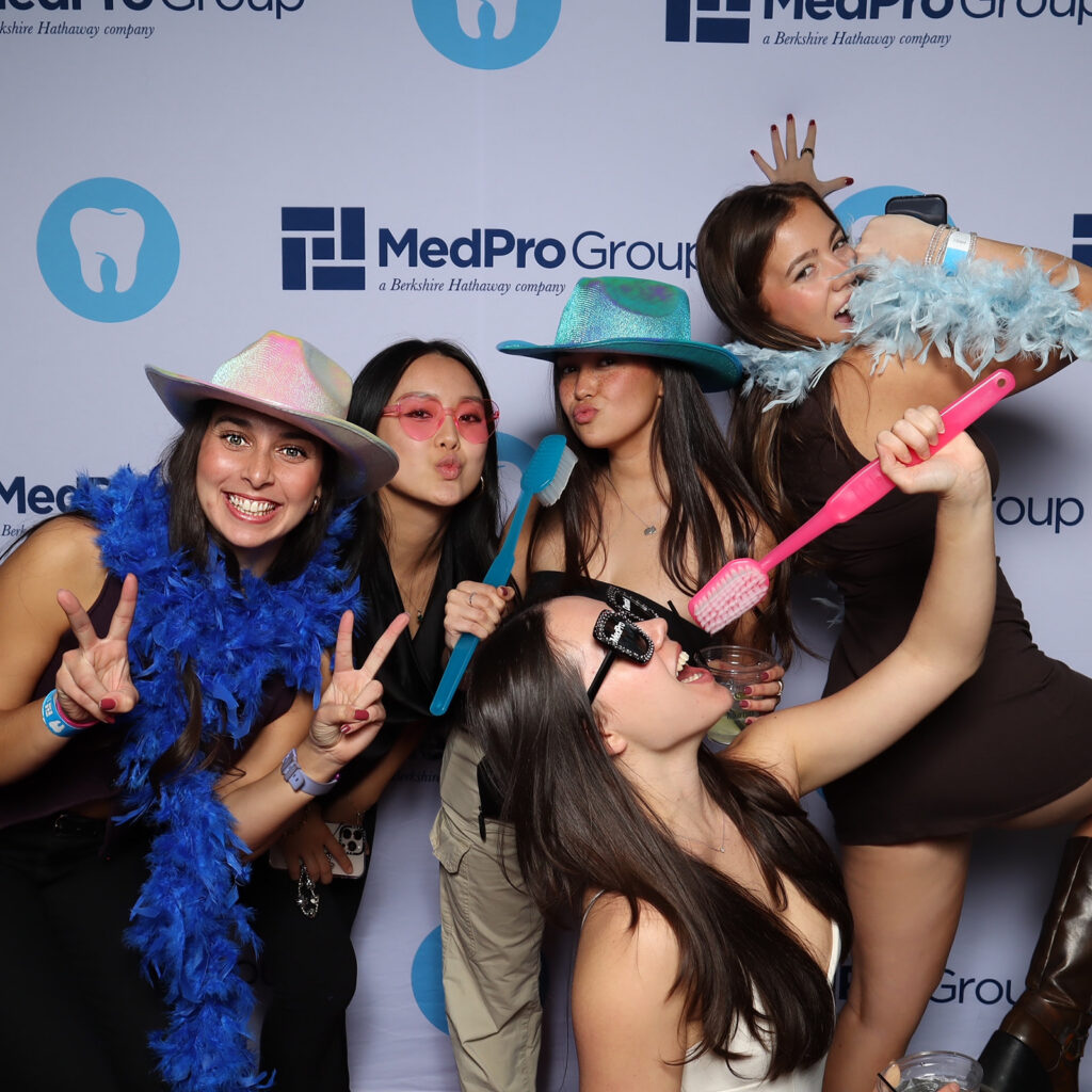Conference photo booth guests posing with props at a MedPro Group branded backdrop in Kansas City